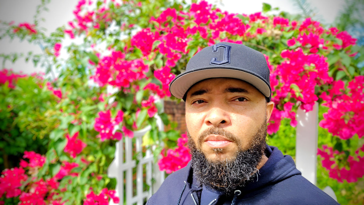 Jermaine Jefferson in his food forest with bougainvillea blooming behind him