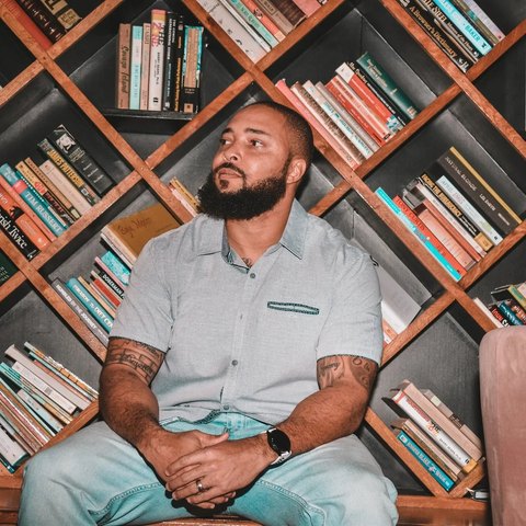 Jermaine Jefferson seated in a coffee shop in front of diagonal wooden bookshelves.